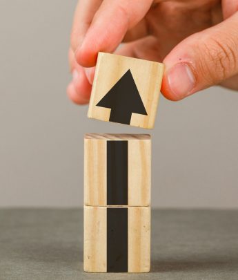 Business growth concept on grey and white background side view. hand putting wood block onto tower.